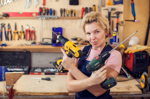 Obraz na plátně Young handy woman with short blond hair working with screwdriver.