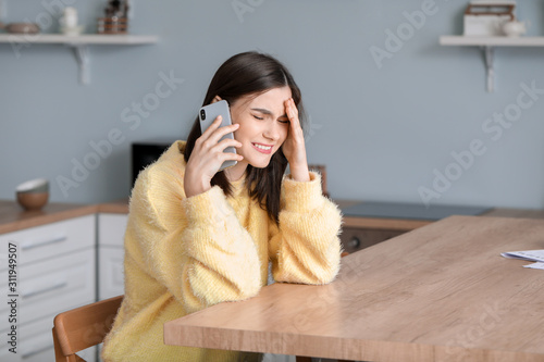 Worried young woman talking by phone at home