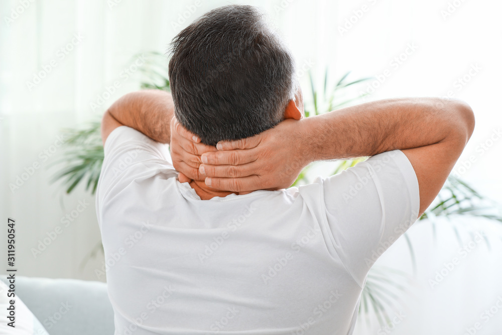 Mature man suffering from neck pain at home Mature man suffering from neck pain at home