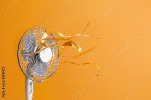 Fotografie, Obraz Electric fan with fluttering ribbons on color background
