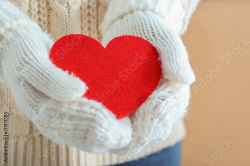 Woman with knitted mittens and red heart  closeup. Valentines Day celebration
