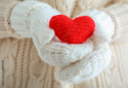 Woman with knitted mittens and red heart  closeup. Valentines Day celebration