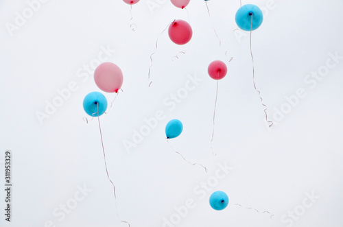 Pink and blue balloons fly up into the sky. Selective focus.