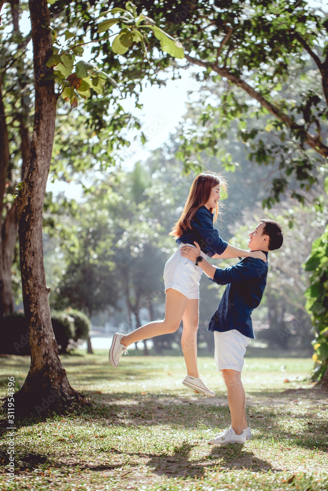 Happy time of a lovely Asian couple in the park on day time, Man hold up his girlfriend.