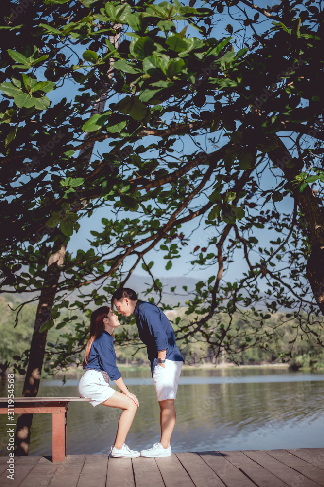 The asian couple will kissing together at park beside the lake.