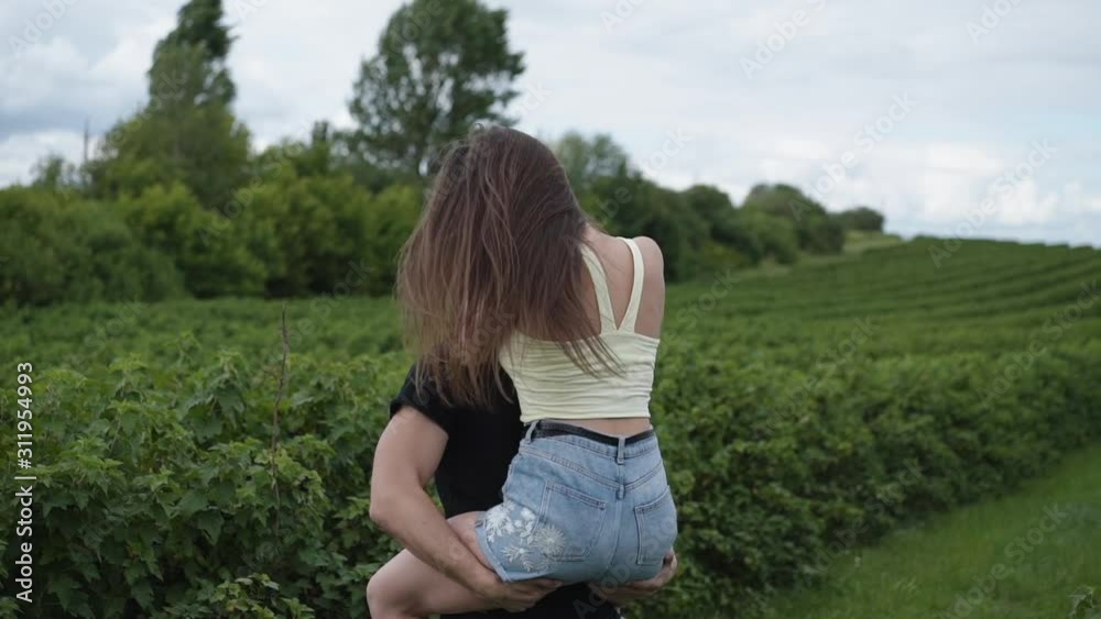 Happy man twisting girl among currant plantation and embracing her Happy man twisting girl among currant plantation and embracing her