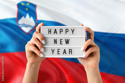 Slovenia New Year concept. Woman holding Happy New Year sign with hands on national flag background. Celebration theme.