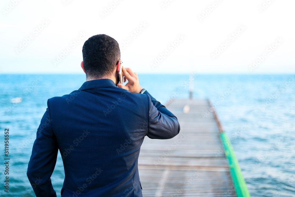 businessman having a call in front of the sea