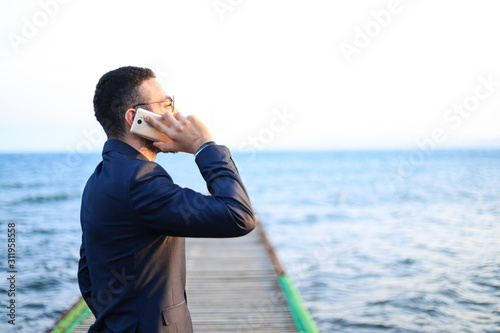 businessman having a call looking into the sea