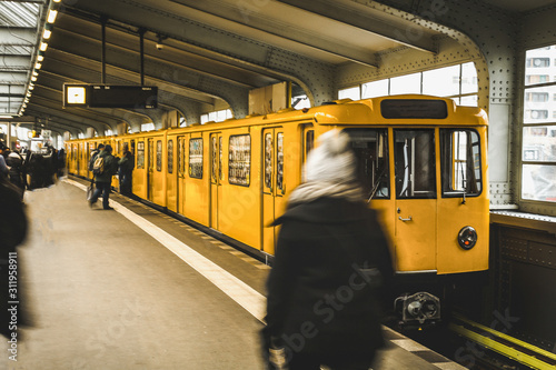 Underground station in Berlin with yellow train and passengers. Public transport in Berlin. Travel and tourism in berlin concept.