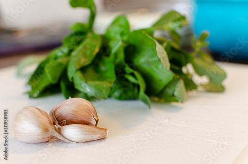 three cloves of garlic with fresh basil leaves
