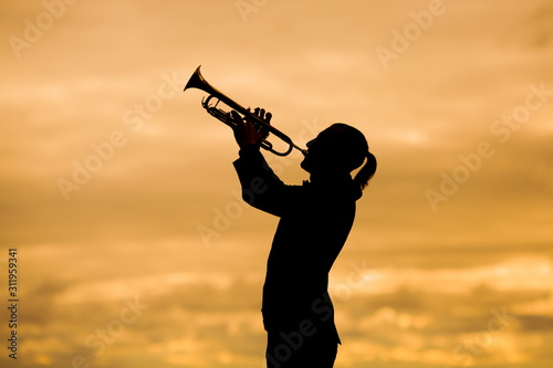 silohuette of man playing trumpet against yellow background