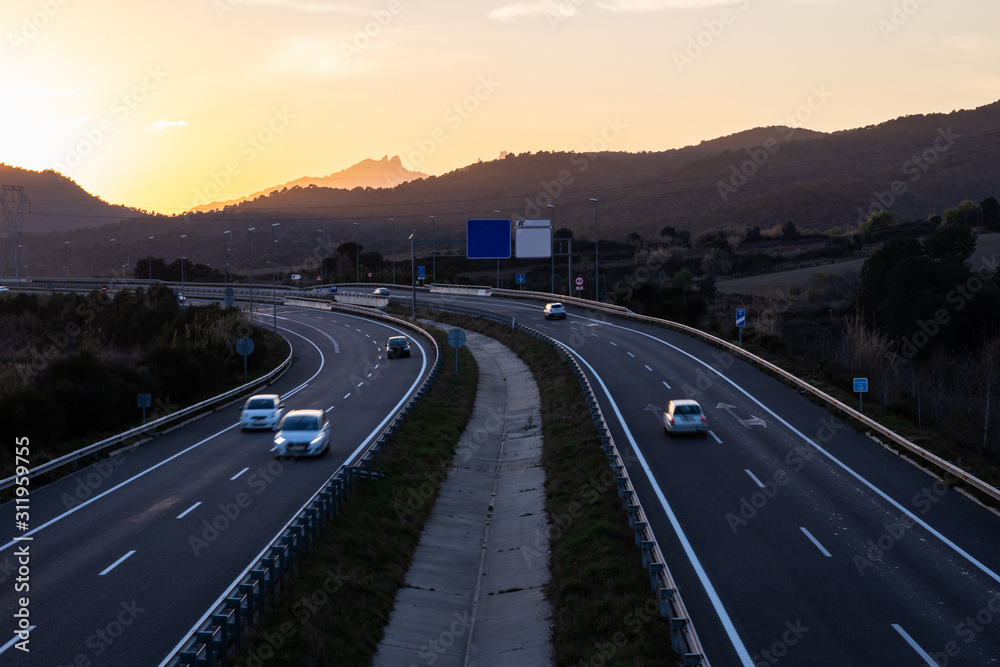 Cars in motion on highway during sunset