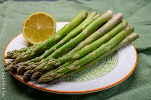 Bunch of fresh green raw organic asparagus with lemon ready to cook