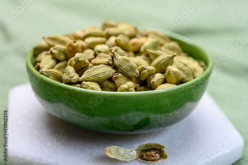 Green pods of cardamom spice in green bowl