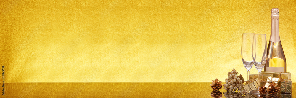 Christmas ornaments, champagne bottle and flutes on gold background. Christmas. New Year. Extra wide panorama banner background Christmas ornaments, champagne bottle and flutes on gold background. Christmas. New Year. Extra wide panorama banner background
