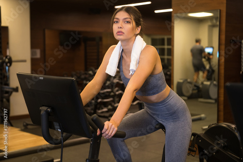 beautiful woman is engaged on a stationary bike in the gym