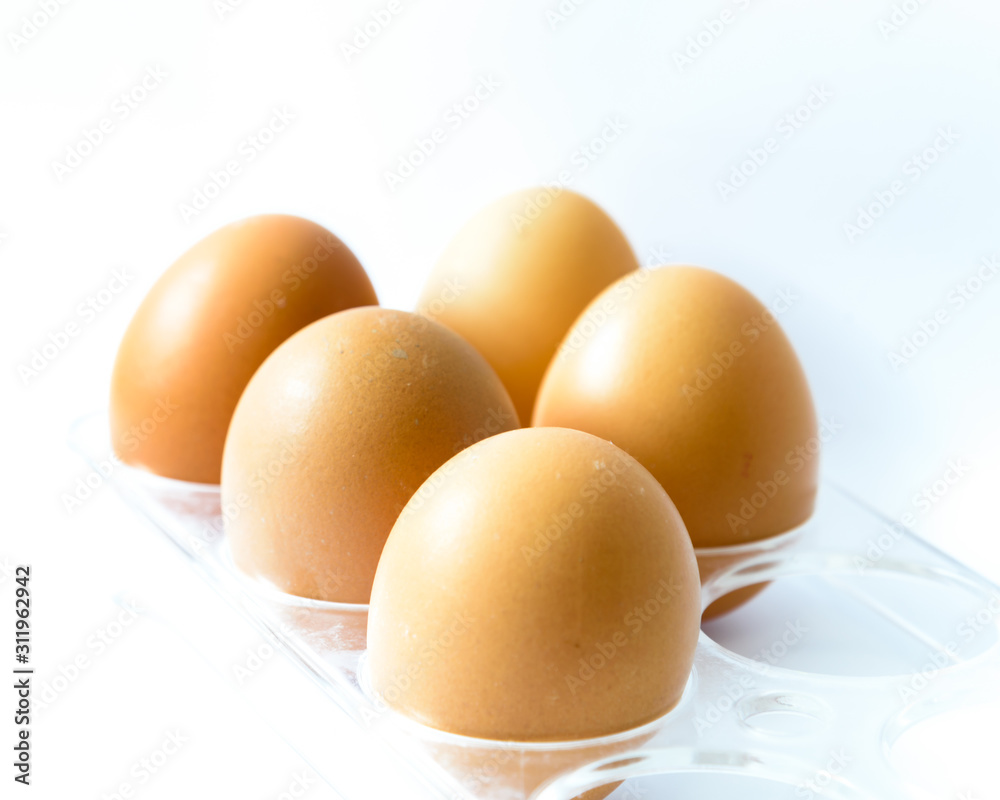 Studio shot five raw brown eggs on plastic package isolated on white
