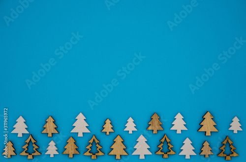 small wooden fir trees at the lower edge in front of a blue background