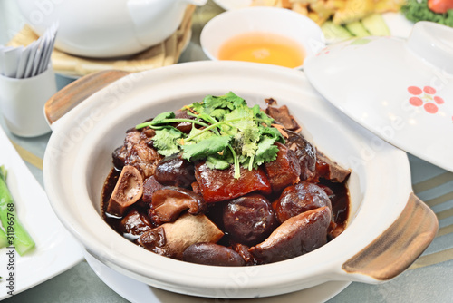 Delicious braised pigs feet in brown sauce in white pot