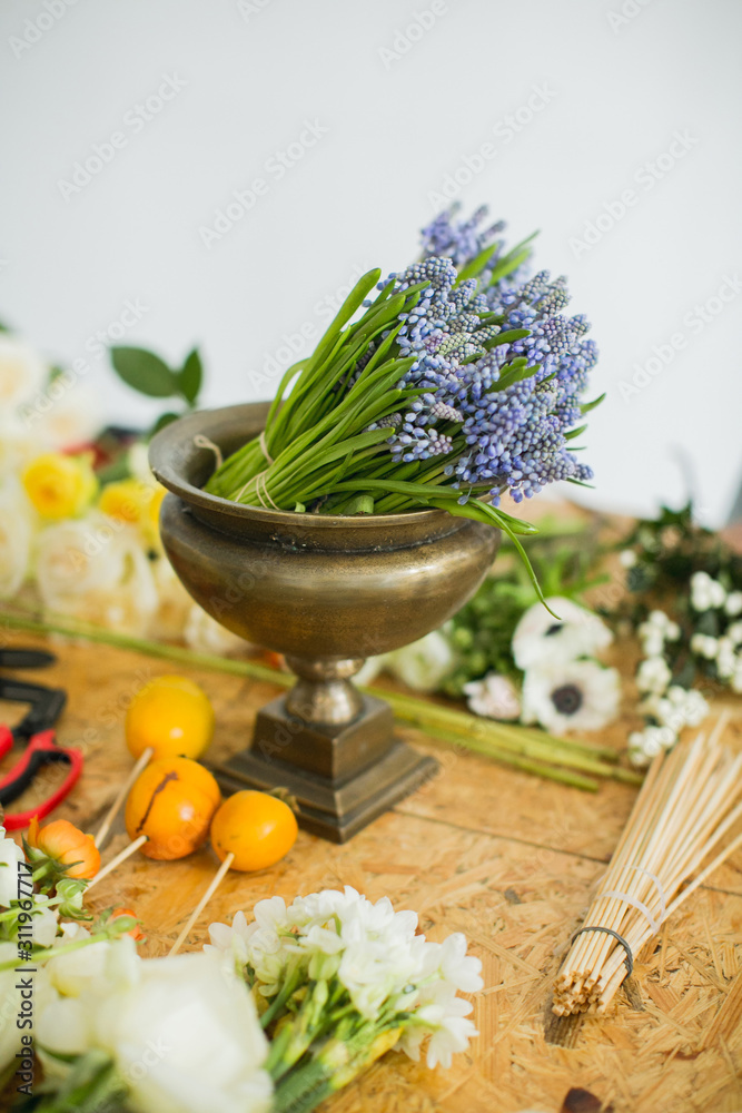 on a wooden table are hyacinths on vase, roses, peonies, daffodils, anemones, and other flowers. Education. Florist communication with customer in the workshop in the studio with flowers. on a wooden table are hyacinths on vase, roses, peonies, daffodils, anemones, and other flowers. Education. Florist communication with customer in the workshop in the studio with flowers.