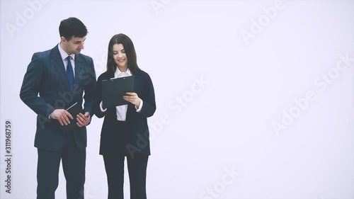 Successful businesspartners standing, looking through the documents, clipped to the clipboard, discussing.