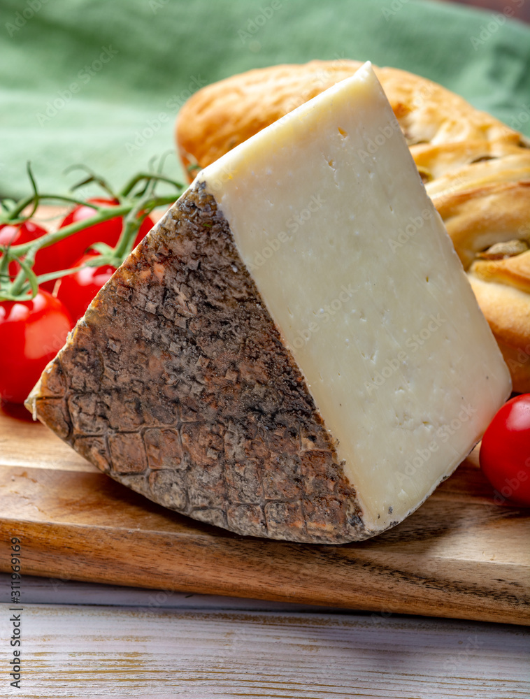 Italian cheese, piece of mature Tuscan Pecorino sheep cheese served with olive bread and tomatoes Italian cheese, piece of mature Tuscan Pecorino sheep cheese served with olive bread and tomatoes