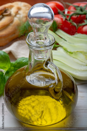 Virgin natural olive oil is glass bottle, served with traditional Mediterranean food