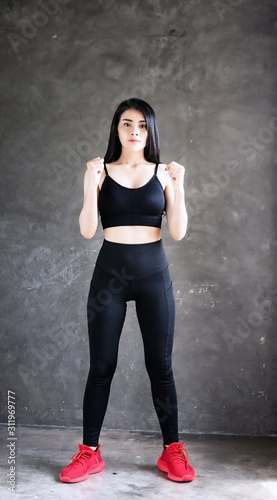 The beautiful woman wearing black exercise suit ,raise fists beside her body,doing exercise at home