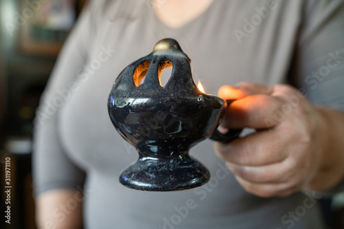 Close up on woman midsection hand holding smoking censer during the slava family's patron saint celebration at serbian home orthodox christian photo