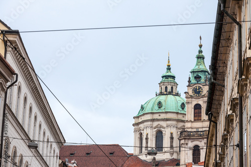 St Nicholas Church, also called Kostel Svateho Mikulase, in Prague, Czech Republic, with its iconic dome seen from nearby streets with typical baroque facade. It's one of main landmarks