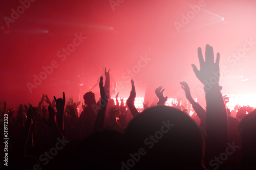 Hands up place for text. Red light. Fans are screaming. Teenagers at a concert copy space. Rock music pattern for design. Musical background.