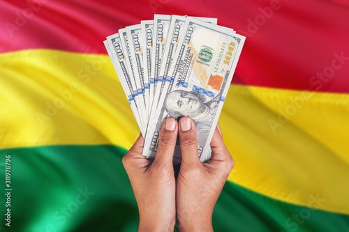 Bolivia financial concept. Female hand holding dollar banknotes on national flag background. Currency and money theme with copy space. photo