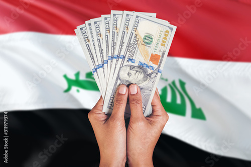 Iraq financial concept. Female hand holding dollar banknotes on national flag background. Currency and money theme with copy space. photo