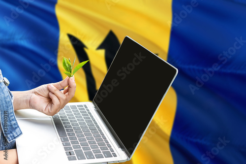 Barbados modern agriculture concept. Farmers holding laptop  check tea on national flag background. Ecology theme with copy space.