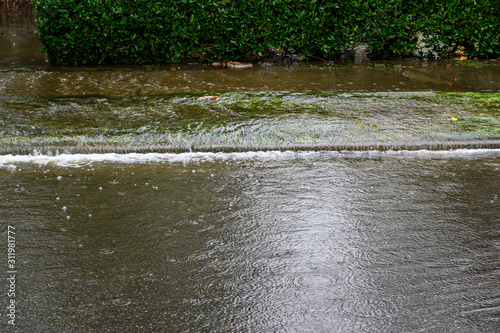 Photo Heavy rain caused flooding over sidewalk, grass strip, and road