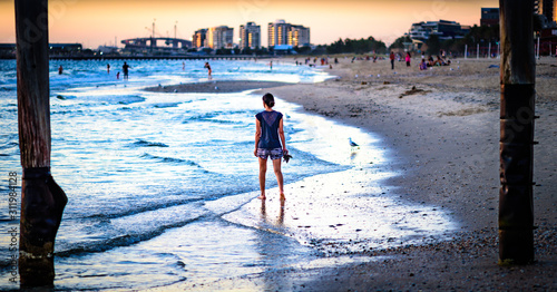 An unidentified female is walking barefoot along South Melbourne Beach during the late afternoon of a hot summer summer's day