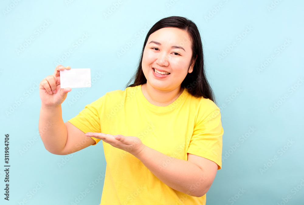 Portrait of happy asian woman holding credit card on a blue background in studio. Portrait of happy asian woman holding credit card on a blue background in studio.