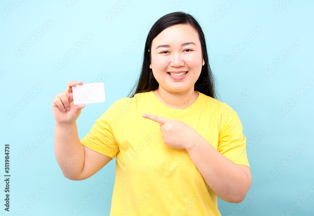 Portrait of happy asian woman holding credit card on a blue background in studio.