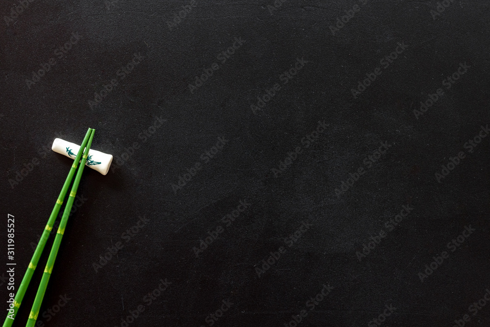 Chopsticks - green wooden utensil for sushi and rolls - on black background top-down copy space