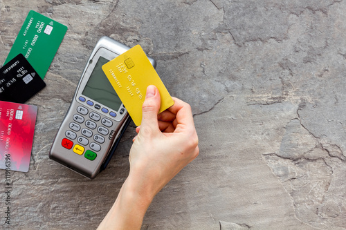 Contactless payment, paypass. Hand hold bank card near terminal on grey stone background top-down copy space
