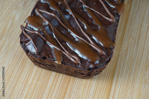 Close up of a moist dark chocolate brownie over chopping board.