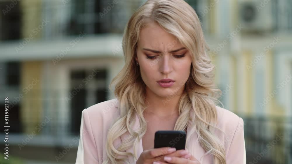Portrait serious businesswoman using smartphone outdoor. Woman typing on phone Portrait serious businesswoman using smartphone outdoor. Woman typing on phone