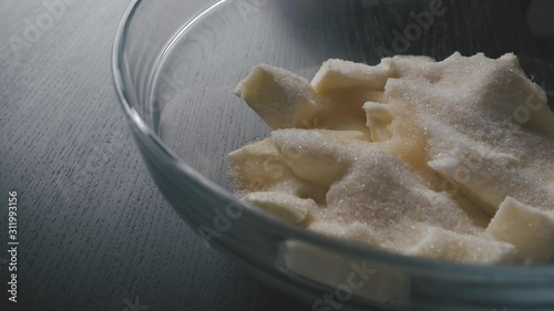 Pouring lemon juice in a bowl of pile of sugar and pieces of butter. Close-up shot photo