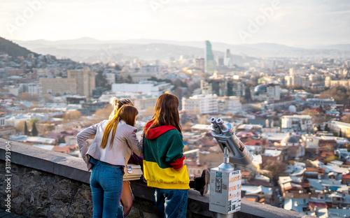 3 teenagers looking at the view of Tbilisi from Narikala Fortress before sunset , Tbilisi , Georgia