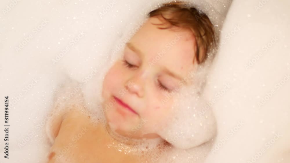 The child takes a bath and plays with foam The child takes a bath and plays with foam