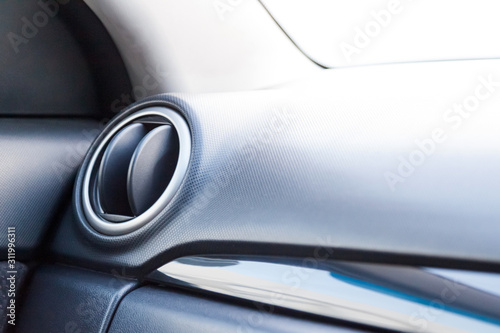 A close-up view of a part of the interior of a modern luxury car with a view of the ventilation deflector of the stove for heating and cooling the passenger compartment with black trim elements © Aleksandr Kondratov