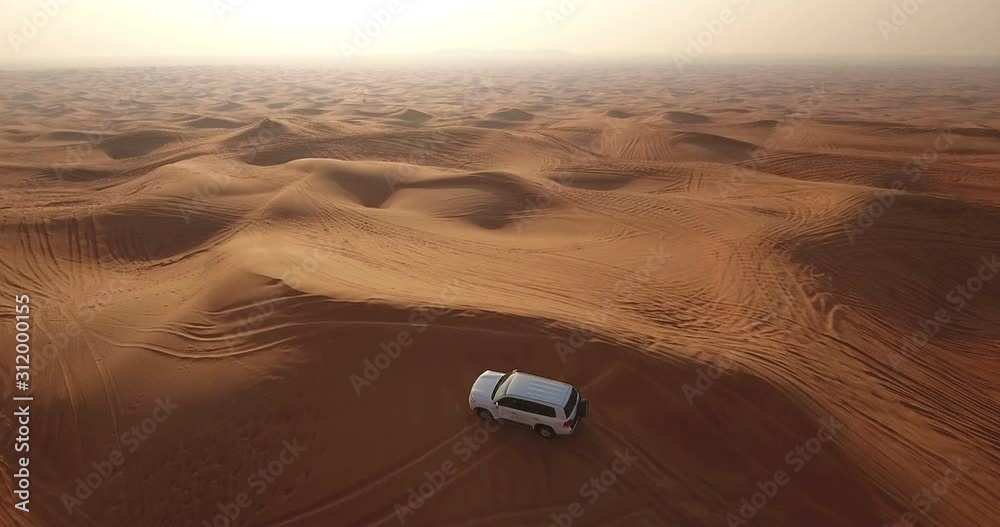 Aerial view of 4x4 off road land vehicle taking tourists on desert dune bashing safari in Dubai, UAE