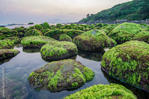 Da Nang beach with moss rocks and waves at sunrise.