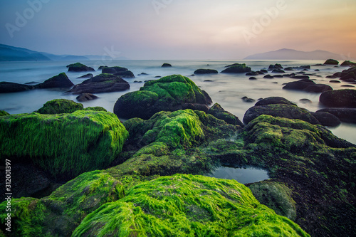 Da Nang beach with moss rocks and waves at sunrise. photo